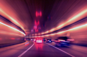 Cars speeding through a traffic tunnel at night