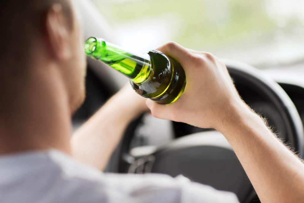 man drinking alcohol while driving the car