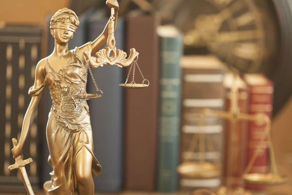 Lady Justice in front of a shelf of law books