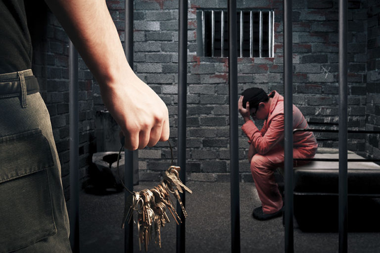 prison guard with keys outside dark prison cell