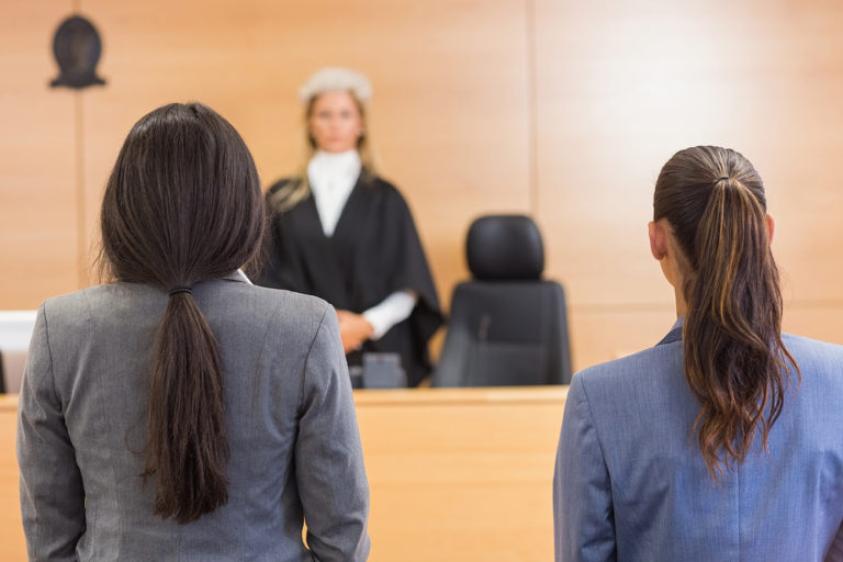 female defendant and her criminal defense attorney standing in front of a judge