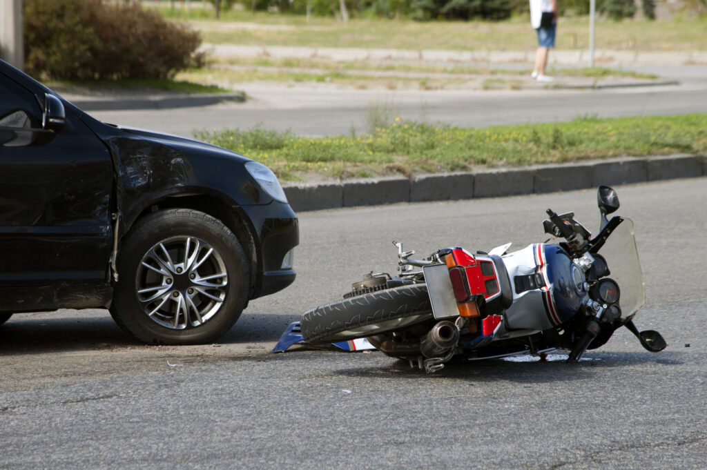 black car near a motorcycle on the road that it hit