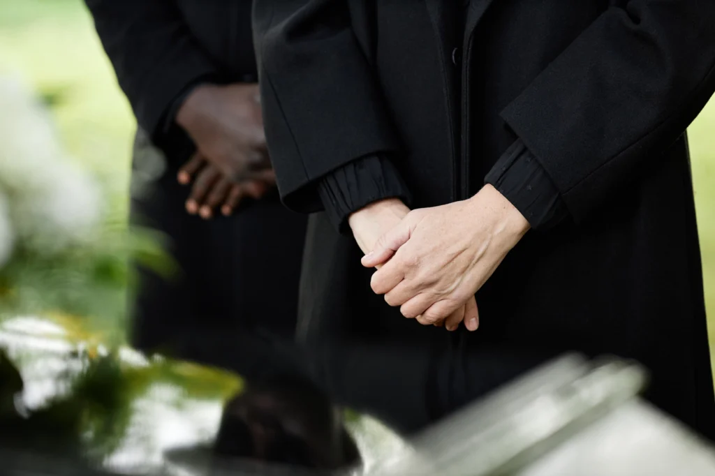 a close-up of hands holding each other at funeral