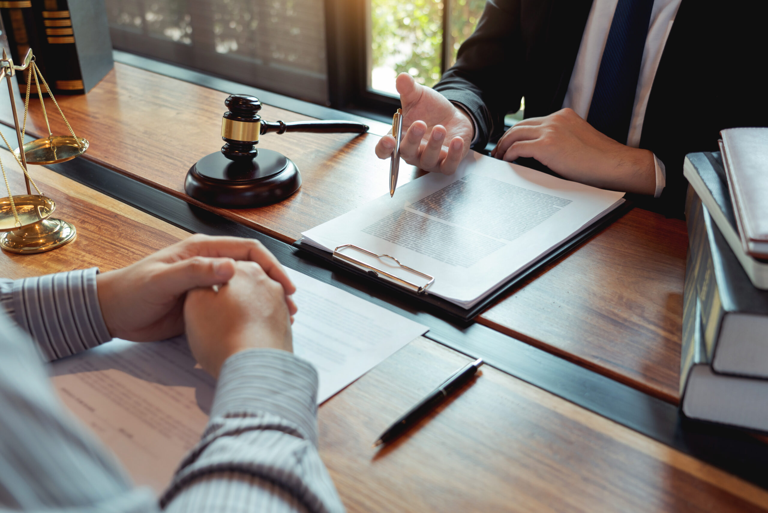 Lawyer working with client discussing contract papers with brass scale about legal legislation in courtroom, consulting to help their customer