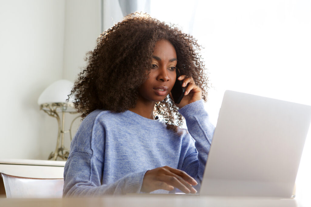 woman talking on mobile phone and using laptop